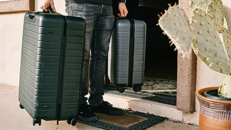 A traveler leaving his home with his two luggage carrying in hand