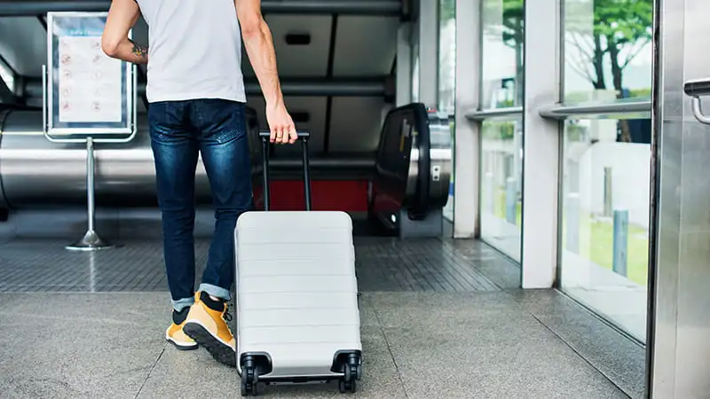 A businessman carrying his stylish white luggage at airport