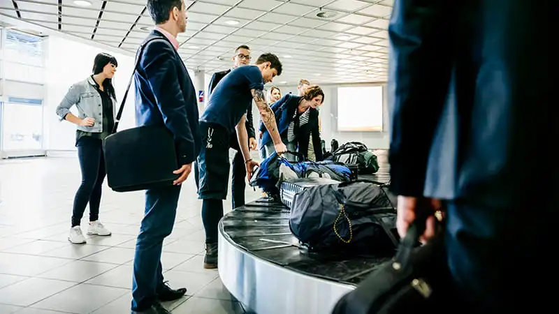 Traveler picking up their luggage from the baggage carousel at the airport