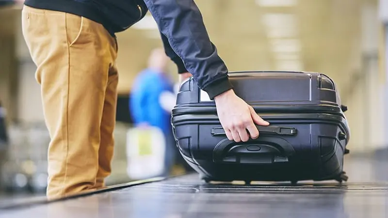 A traveler is pickin up his luggage from the baggage carousel at the airport