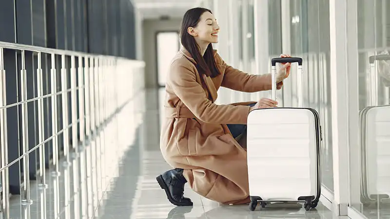 A women feeling overwhelmed because of her stylish white luggage at the airport