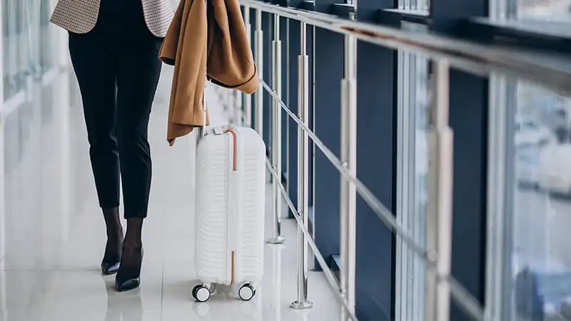 A business women traveling with her white luggage at airport